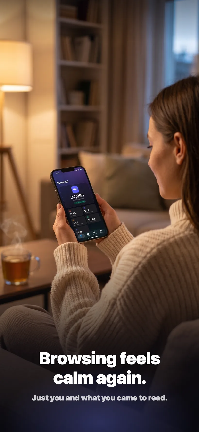 A woman relaxing on a couch in the evening, reading on her iPhone with the Blindfold app open showing her monthly blocking stats.